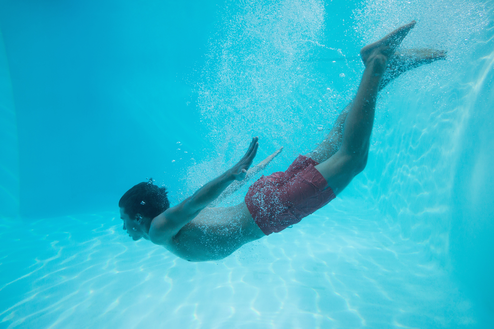 Full length side view of a young man swimming underwater